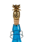Blue bottle with a gold pineapple-shaped cork stopper on a white background
