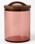 Pink glass jar with a wooden lid on a white background