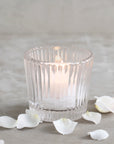 Pressed glass candle holders with textured walls with a lit votive candle