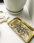 Gold jewelry tray with snake design on a white surface