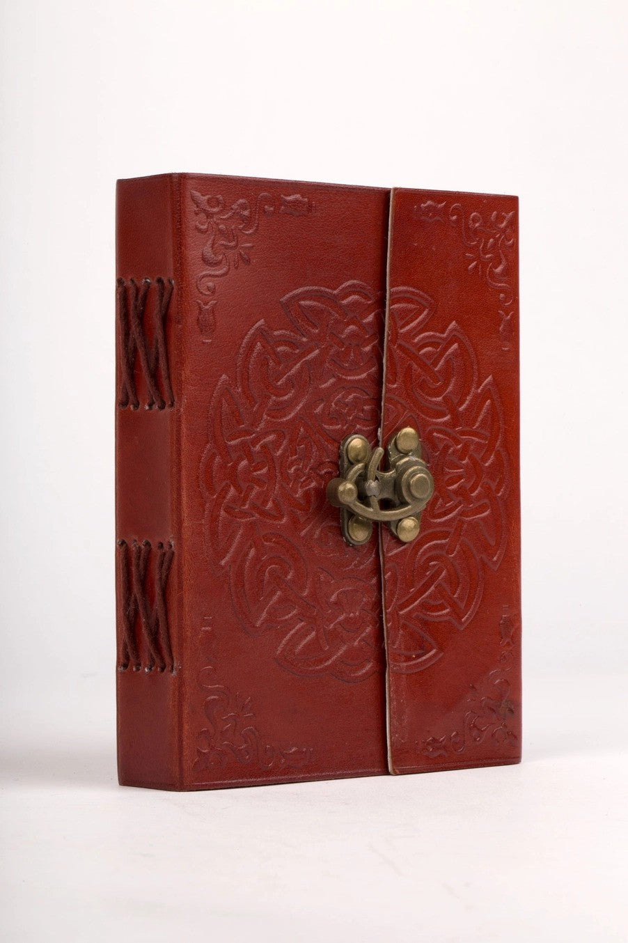 Red leather-bound book with embossed design and brass clasp on a white background