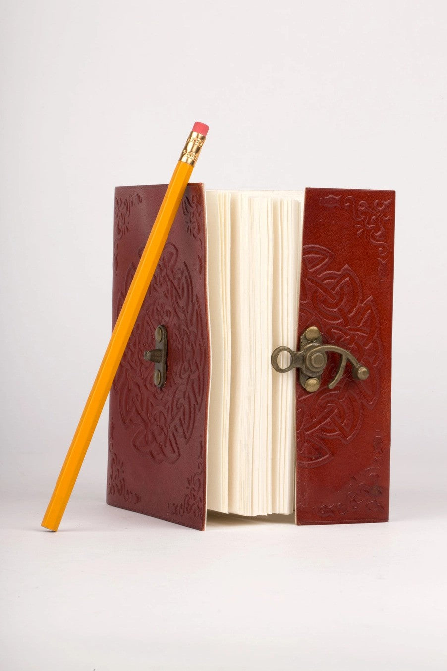 Decorative leather notebook with intricate patterns and a yellow pencil on a white background