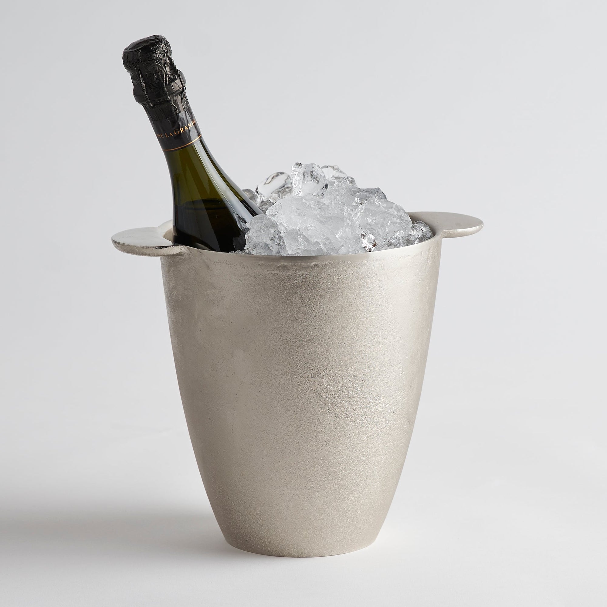 A silver aluminum ice bucket with smooth tab handles, containing a bottle of champagne on ice