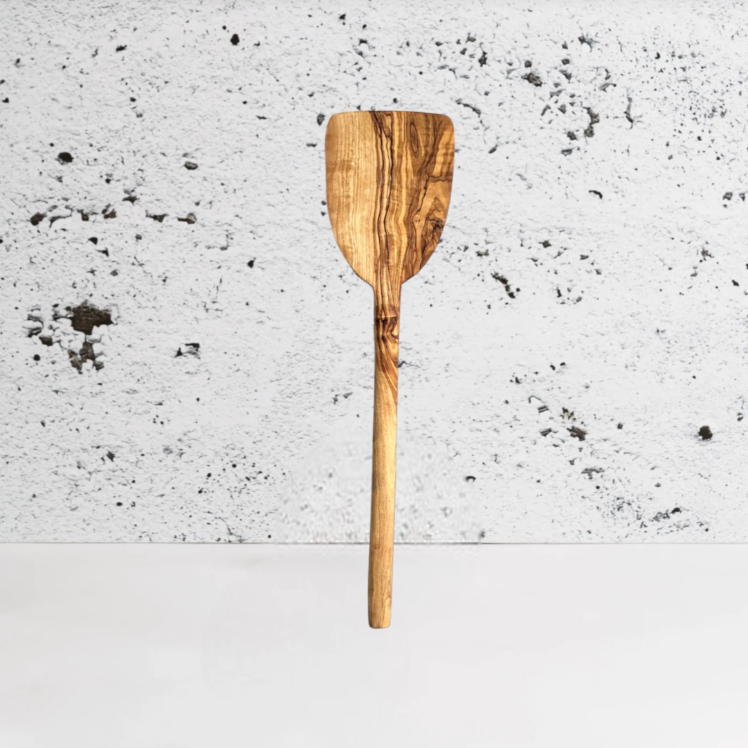 Olive wood pancake spatula against a textured gray background