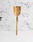 Olive wood pancake spatula against a textured gray background