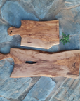Two olive wood cutting boards displayed on a blue stone background