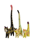 A set of three hand-painted wooden cat figurines in varying colors, with long tails and distinctive patterns on their bodies