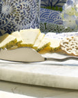 Cheese platter with sliced cheese, crackers, and a silver knife on a marble surface