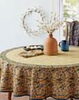 A round white sola wreath in the background of a room that has a table and dried flowers in a vase