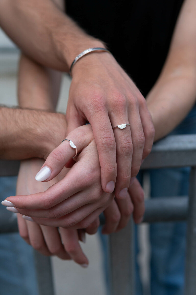 Four hands together wearing .925 sterling silver ring sets.