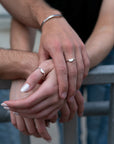 Four hands together wearing .925 sterling silver ring sets.