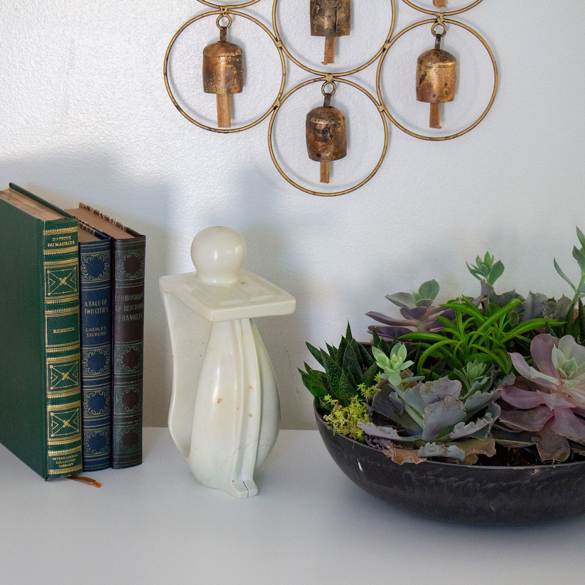 Handmade stone sculpture of a person in a thoughtful pose next to three books