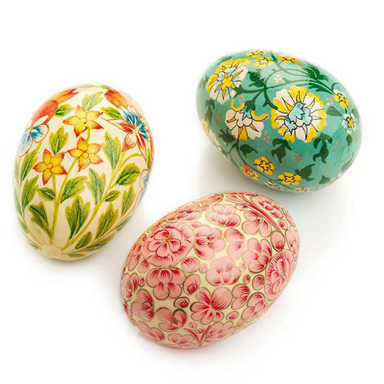 A set of three hand-painted wooden eggs, each with a different floral pattern, in green, white, and pink colors