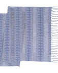 A blue and white striped table runner with fringe, laid out flat