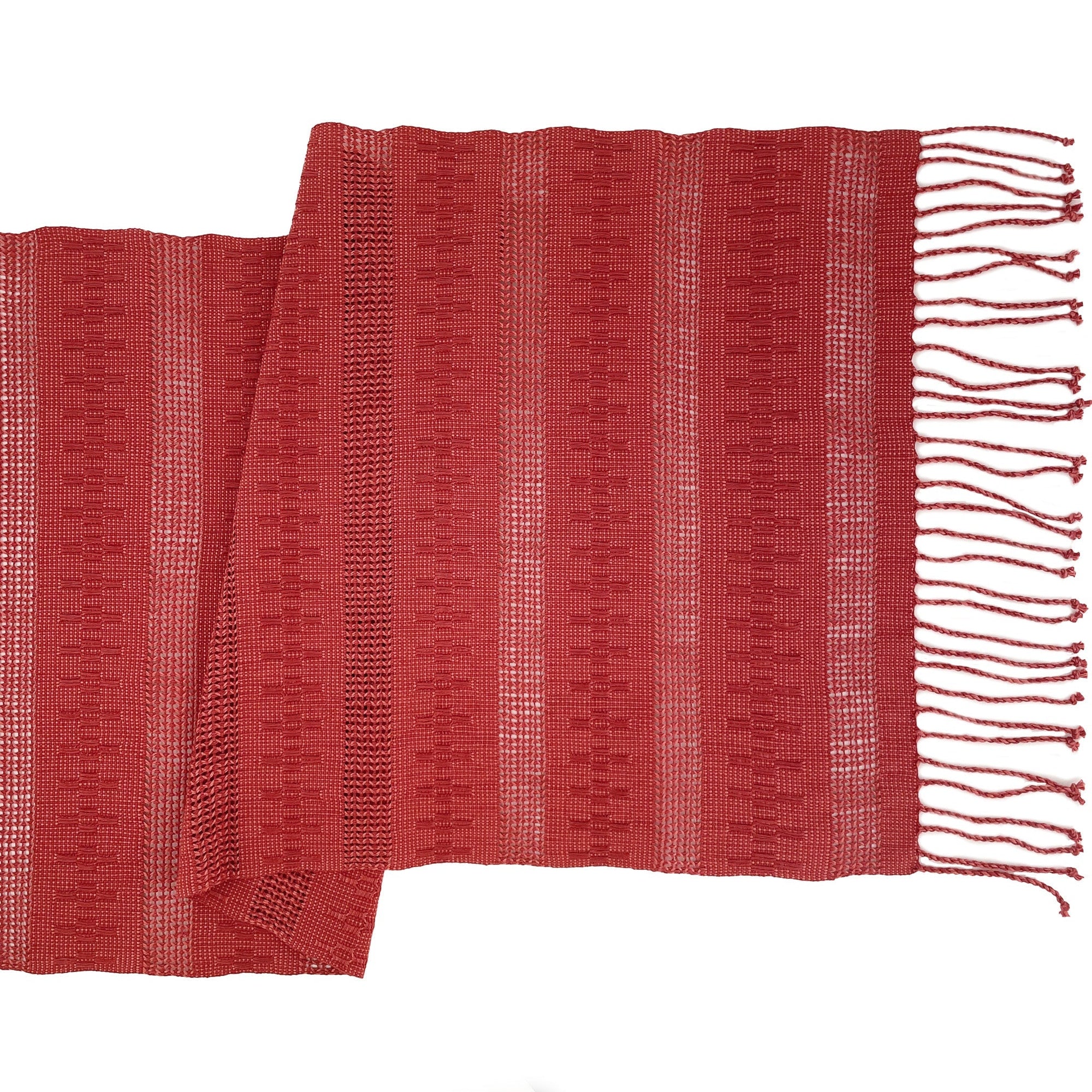 A terracotta-colored table runner with a striped pattern and fringed ends, laid out flat