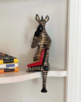 A handmade wooden zebra ledge lounger on a shelf
