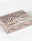Decorative wooden box with intricate tree carvings on a white background