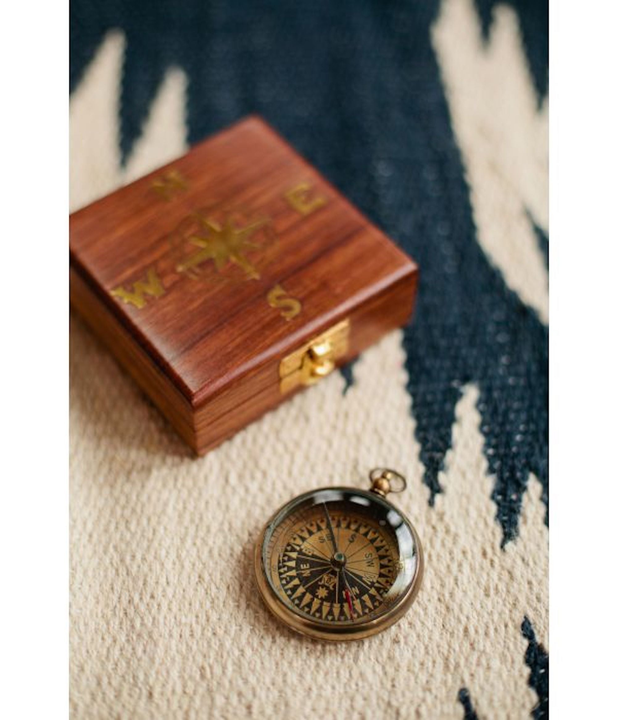 A navigational compass with a sheesham wood box, featuring a metal body and a glass face, with the box closed and the compass next to it.