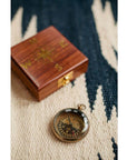 A navigational compass with a sheesham wood box, featuring a metal body and a glass face, with the box closed and the compass next to it.