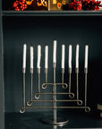 Decorative menorah with white candles on a shelf with a dark background