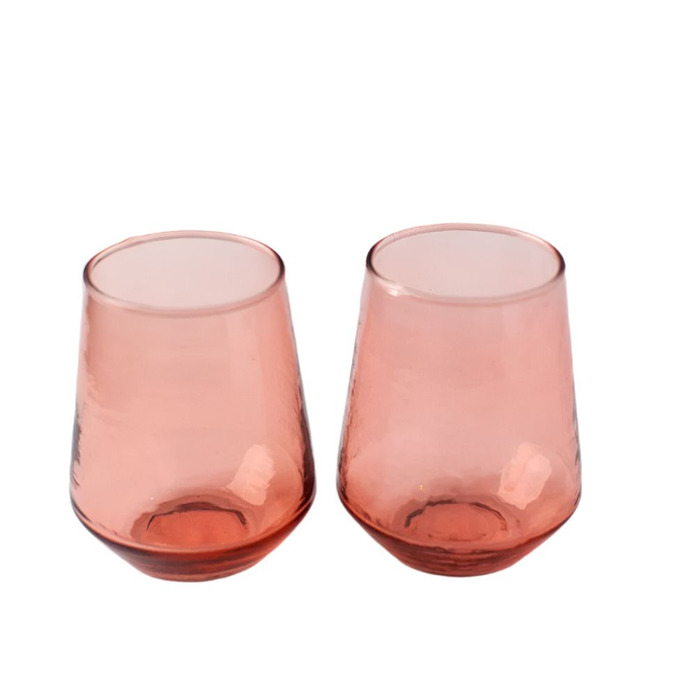 Two handblown hammered blush pink drinking glasses with a textured finish, set on a white background