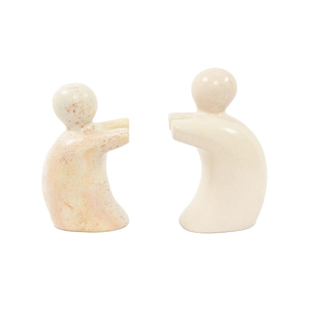 A pair of hand-carved soapstone bookends in the shape of abstract sculptures of people helping to hold up a book