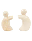 A pair of hand-carved soapstone bookends in the shape of abstract sculptures of people helping to hold up a book