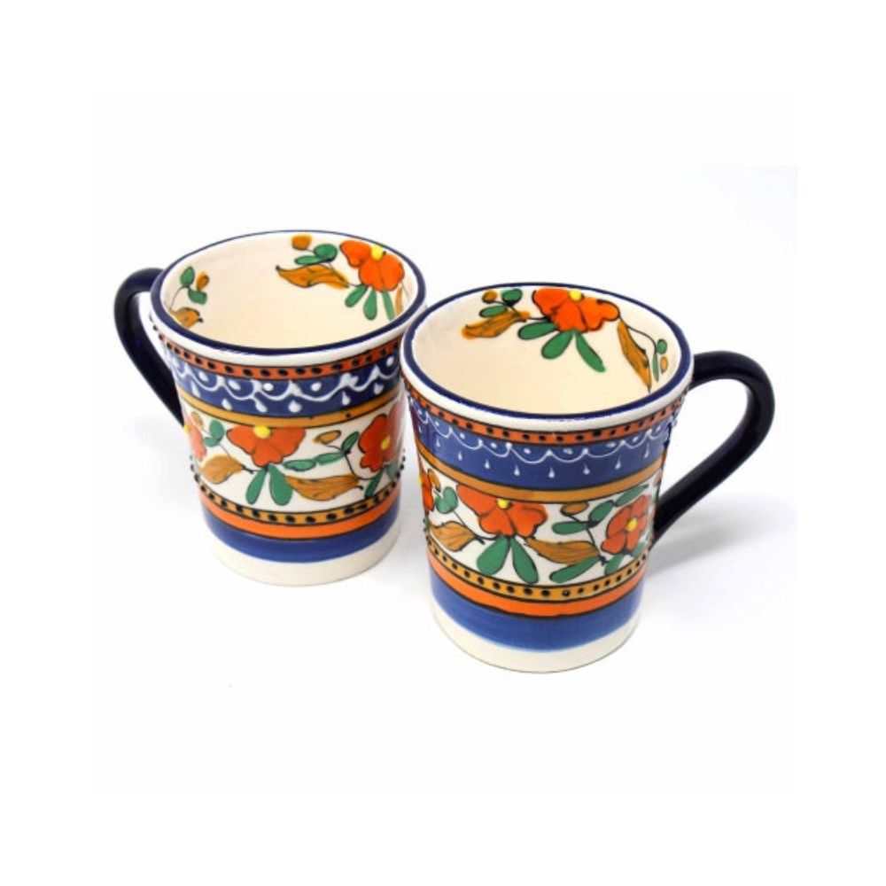 A set of two handcrafted orange and blue ceramic coffee mugs with floral patterns and textured surfaces.