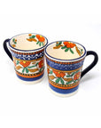 A set of two handcrafted orange and blue ceramic coffee mugs with floral patterns and textured surfaces.
