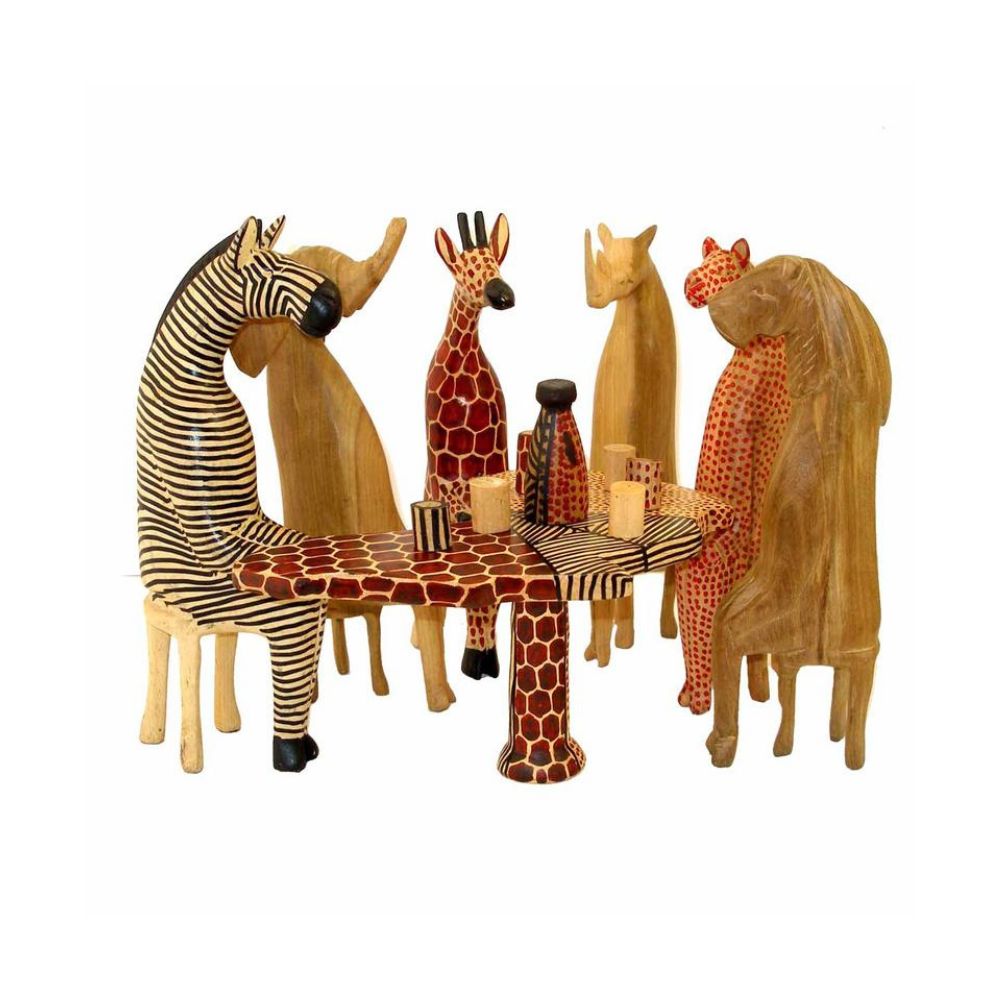 A set of hand-carved wooden animals, including representations of a zebra, giraffe, elephant, and others, seated around a table with patterned wooden glassware