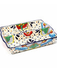 A colorful handmade ceramic platter with a geometric dot and flower pattern, featuring a division for serving