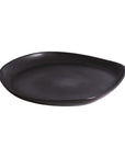 A round, black stoneware serving platter with a simple and elegant design, hand-crafted with visible edges and a smooth surface