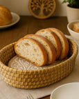 Sliced bread in a woven basket on a wooden table with a knife and fork.