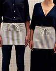 Two people wearing a striped waist apron with pockets.
