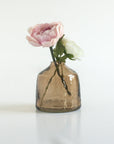 Smoked glass vase with a single pink flower on a white background
