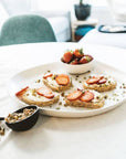 A white ceramic serving platter with toast and a bowl of fruit on top