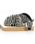 A sculpture of a striped zebra resting its head on a wooden shelf, made from natural soapstone