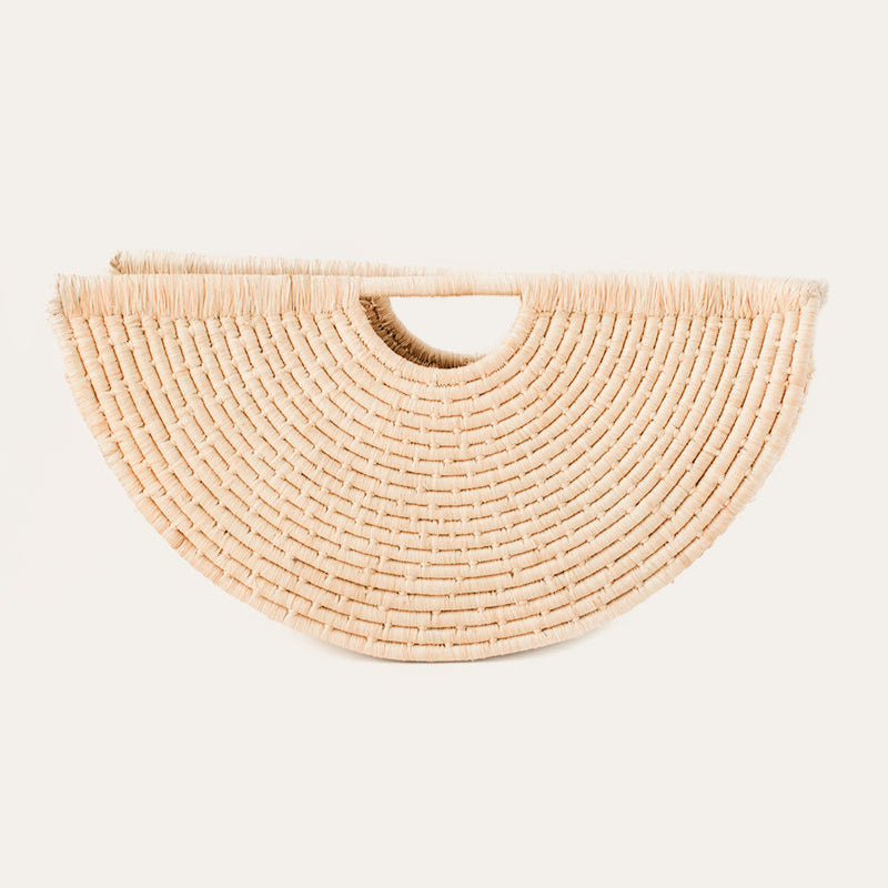 A beige, geometric, shell-shaped hand tote bag made from woven raffia.