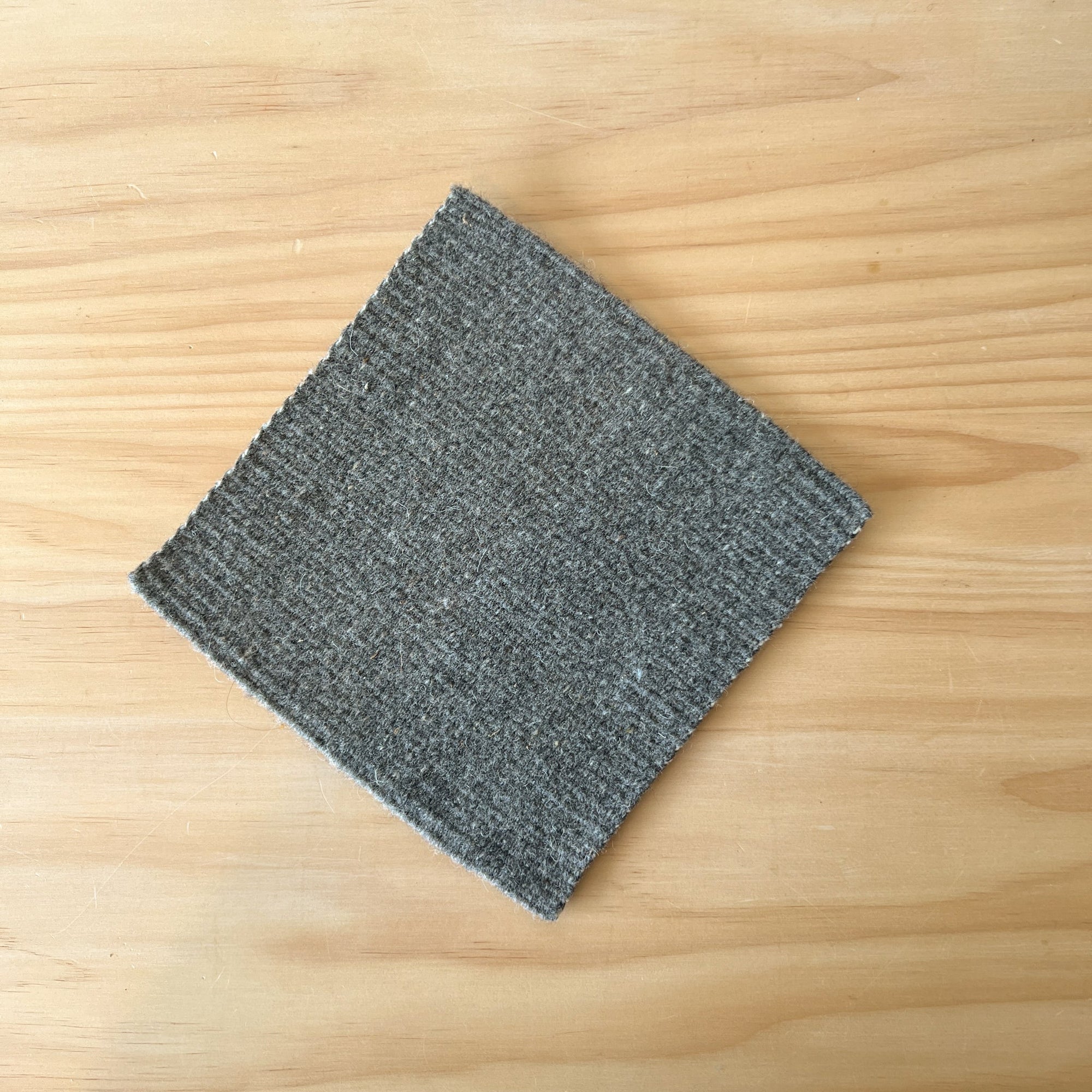 Gray wool trivet on a wooden surface