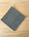 Gray wool trivet on a wooden surface