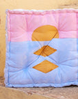 Colorful floor cushion with geometric patterns on a textured surface