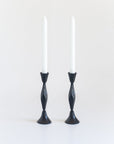 Two black candle holders with white candles on a white background
