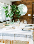 Striped cotton tablecloth laid on a rectangular table showcasing candles, plates, and chargers