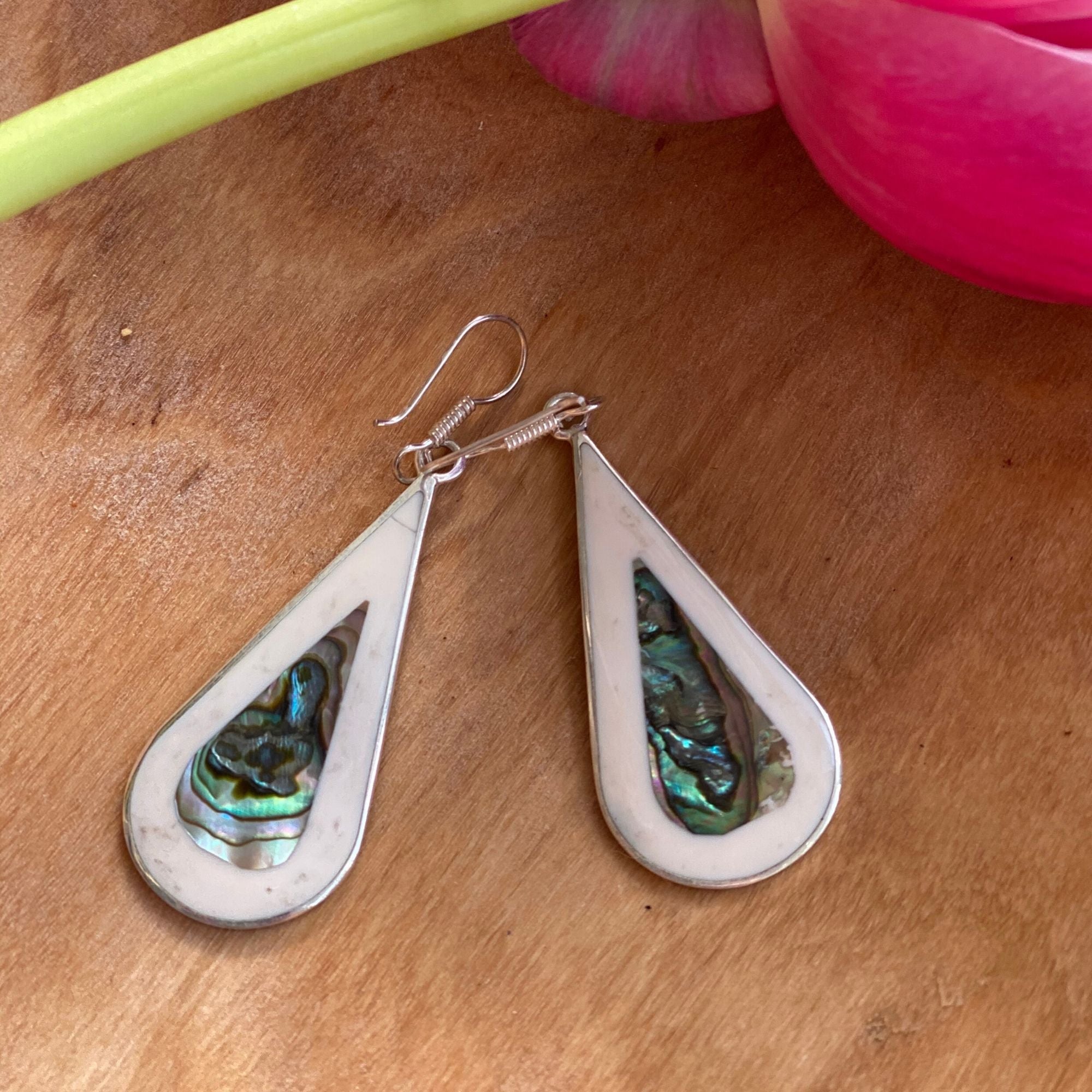 Sterling silver abalone and Mother-of-Pearl shell earrings on a wooden desk.