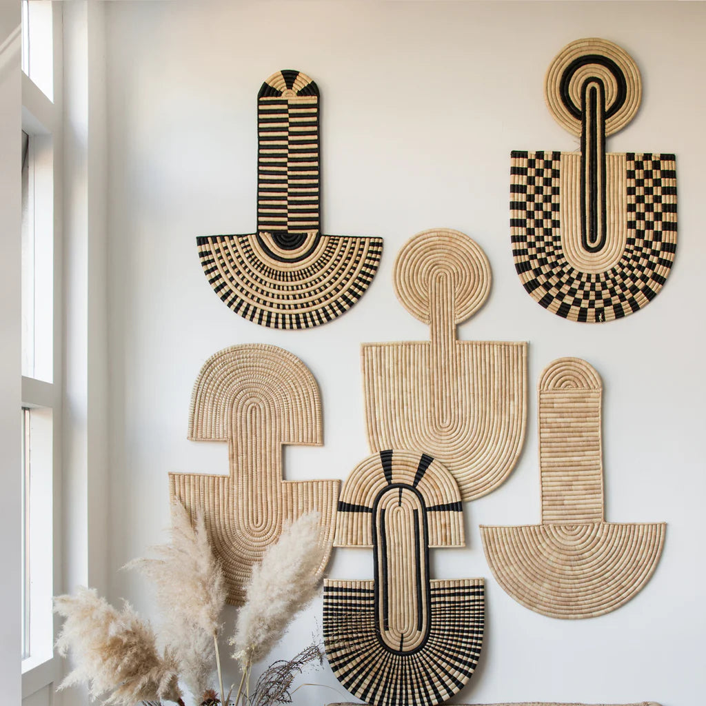 Multiple woven abstract wall masks with geometric patterns displayed on a white wall