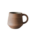A brown ceramic mug with visible earth tones and textures, handcrafted with a ribbed design and a handle on the side
