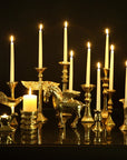 Decorative candle holder with winged creatures and lit candles on a reflective surface.