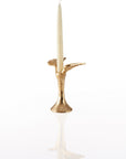 Gold candle holder designed with angel wings with a white candle on a white background