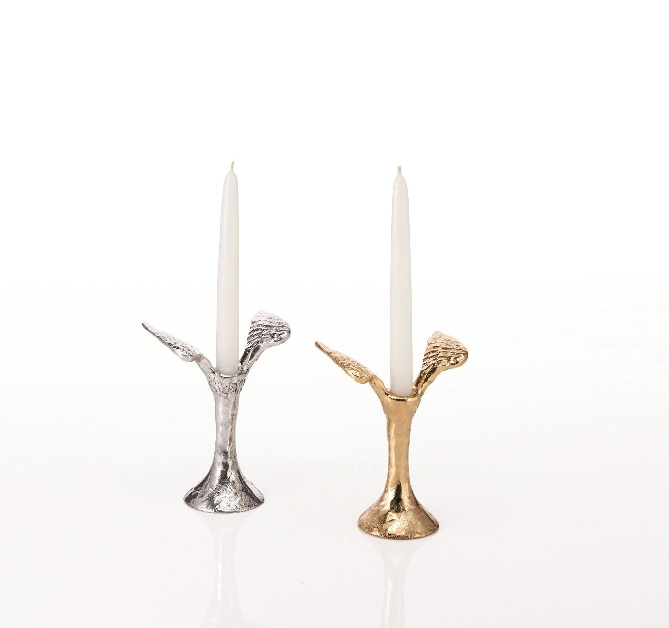 Two candle holders with angel wings, one silver and one gold, with white candles on a white background.