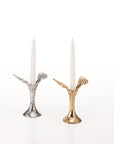 Two candle holders with angel wings, one silver and one gold, with white candles on a white background.